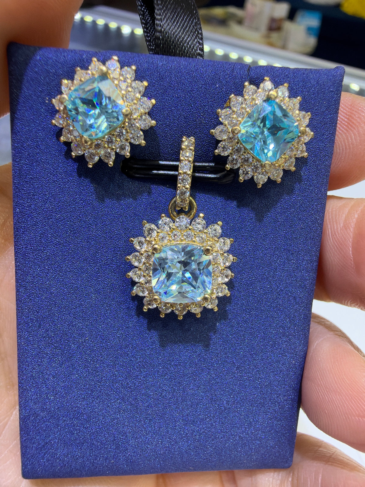 14k Earring and pendant in blue aquamarine gems set in a floral-inspired sunburst halo design consisting of an inner ring of smaller round accents and an outer scalloped border of marquise-shaped